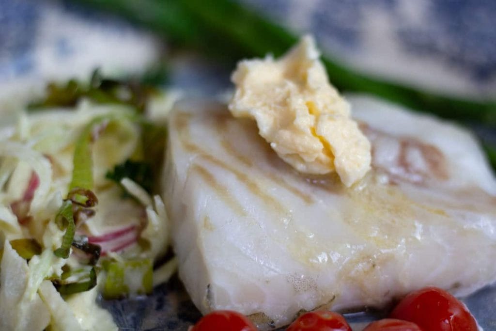 a side view horse radish butter melting on a hot fillet of cod