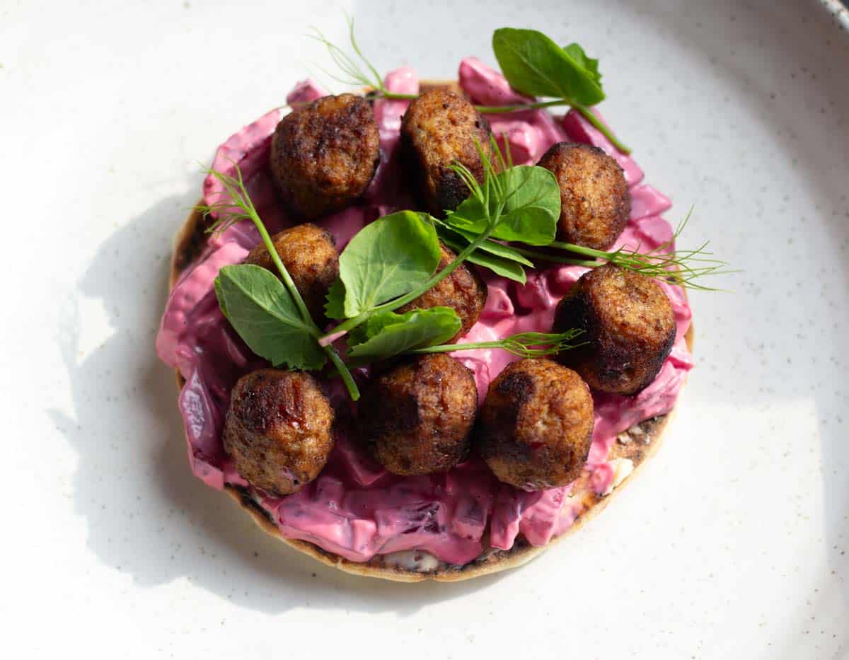 A Swedish meatball sandwich garnished with fresh pea shoots from the garden