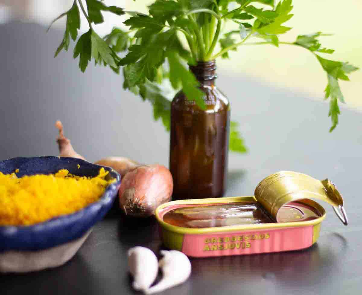A bowl of yellow mustard, a bottle of mustard, and a plant.