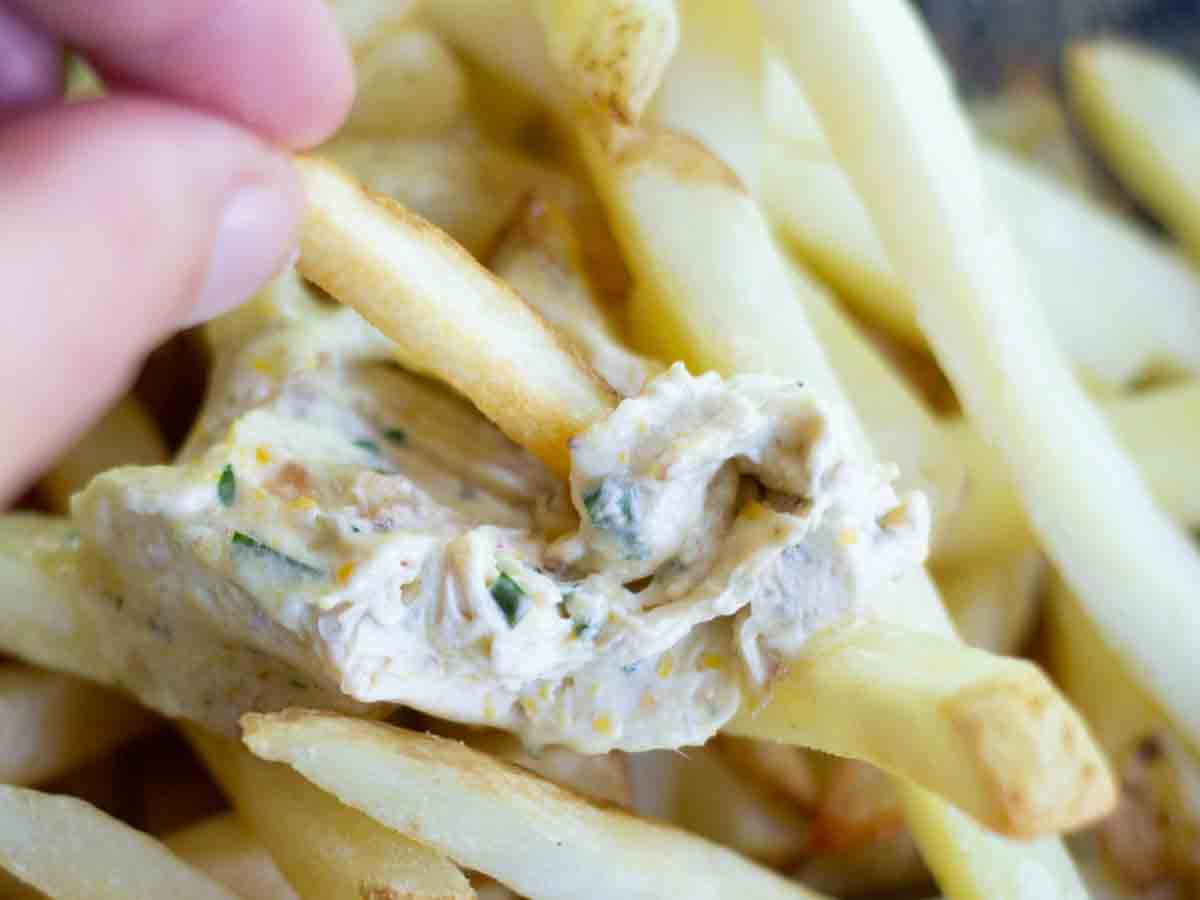 a hand dipping a fry in butter of the gods