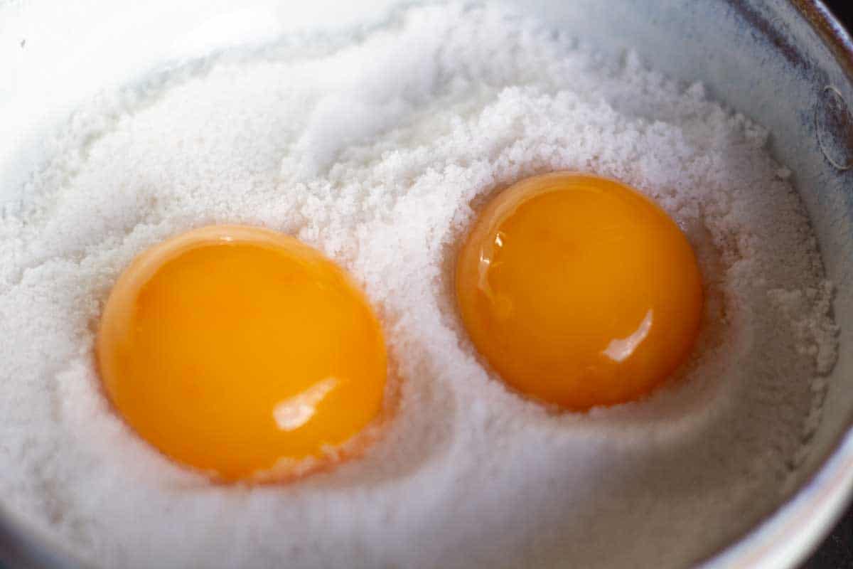 two egg yolks in salt in a ceramic bowl