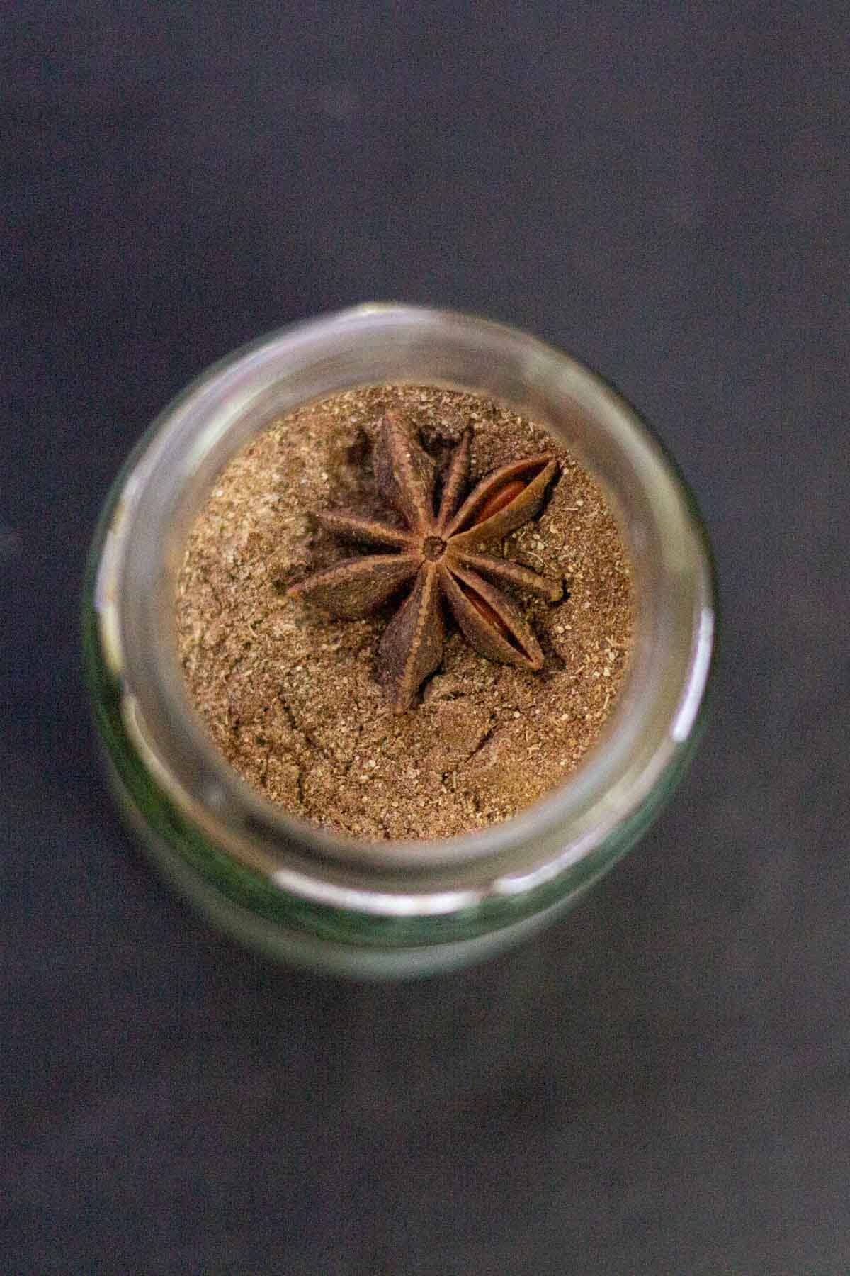 overhead view of a glass jar filled with gingerbread spices and topped with a star anise