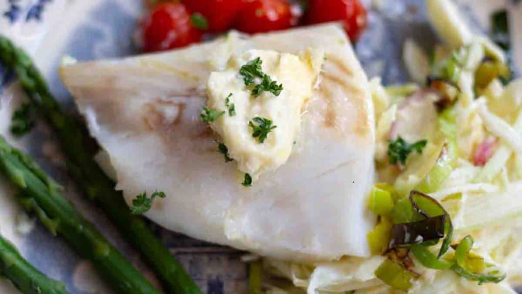 horseradish butter on grilled fish beside asparagus, tomatoes adn a green salad
