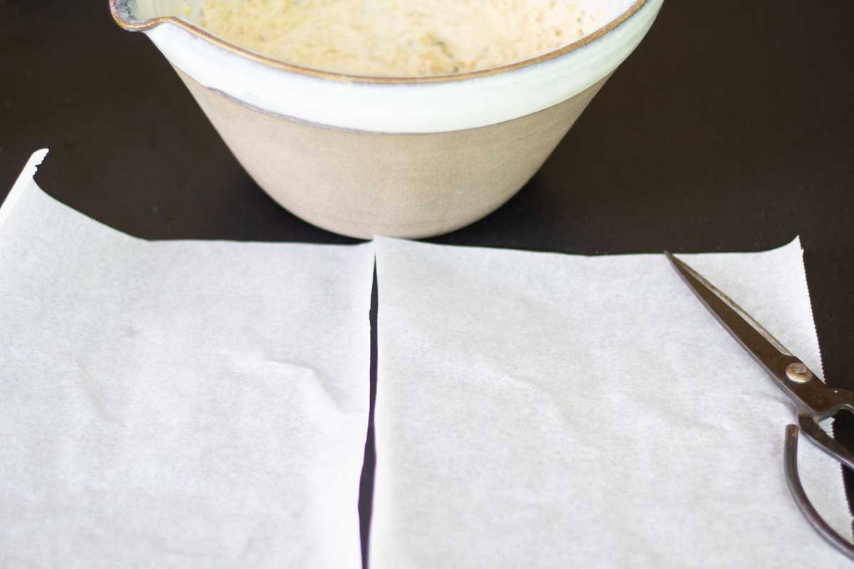 two sheets on parchmet paper beside a large ceramic bowl of butte rof the gods
