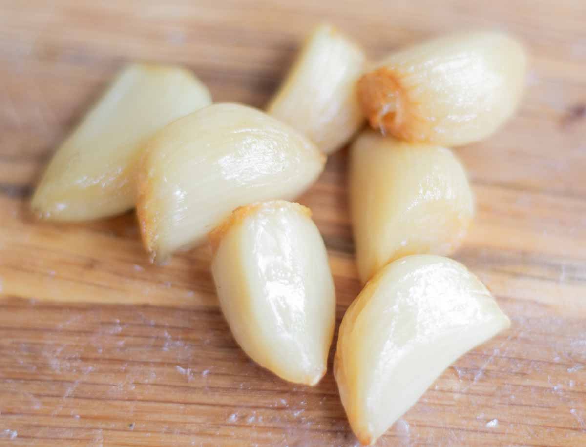 roasted garlic cloves on a wooden chopping board