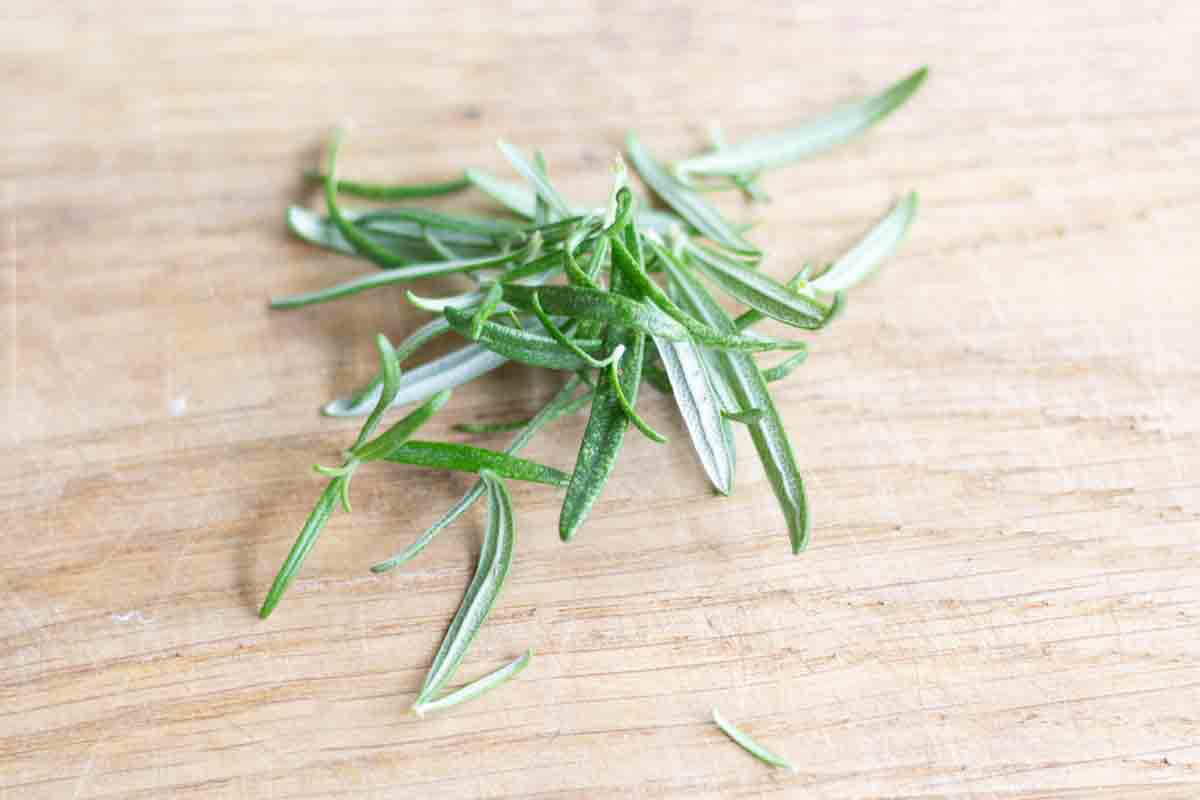 fresh rosemary leaves on a wooden chopping board
