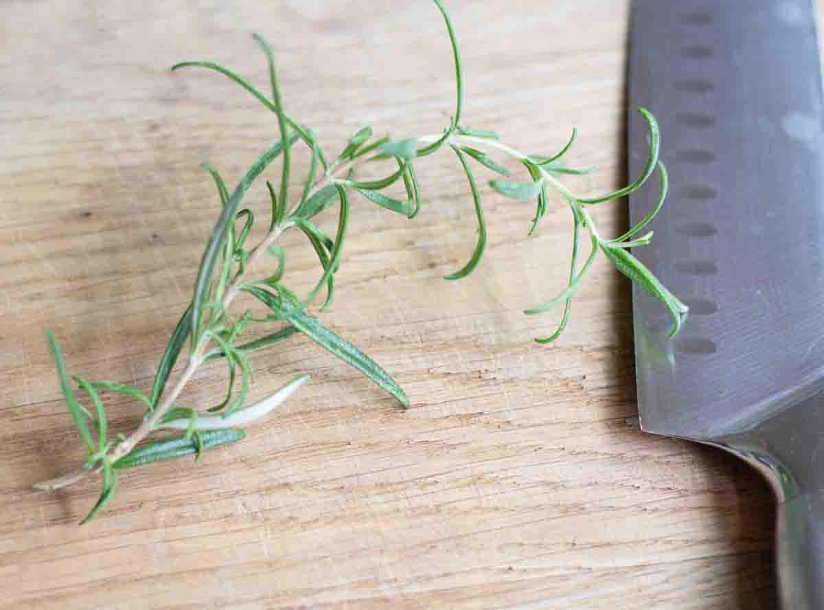 fresh rosemary on a wooden chopping board with a sharp knife