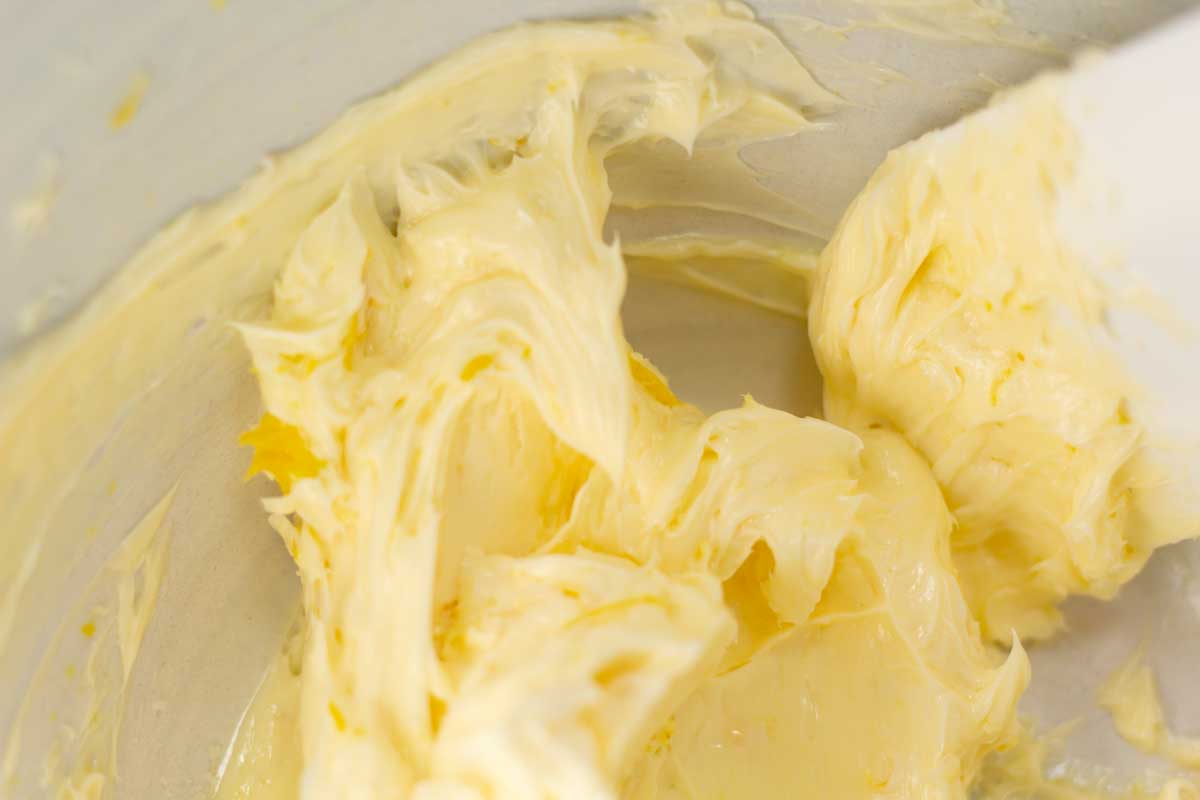 A spatula scraping downt butter from the sides of the bowl