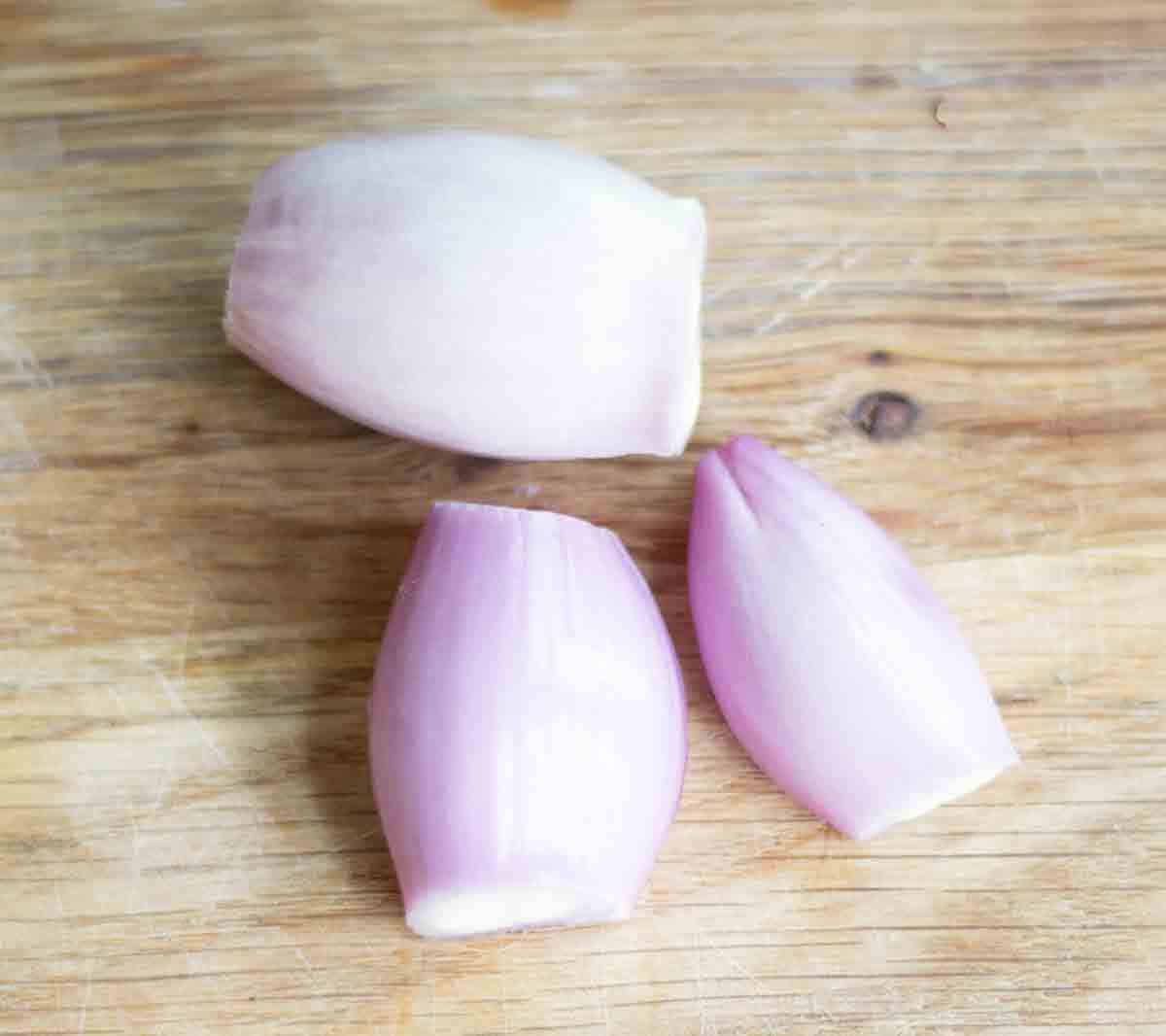 peeled shallot onions onions on a chopping board