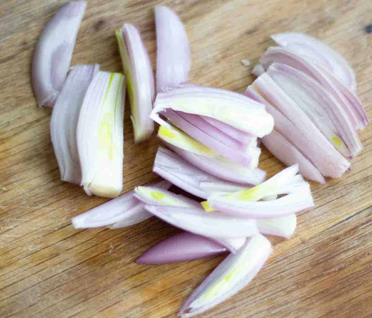 short onions sliced on a wooden chopping board
