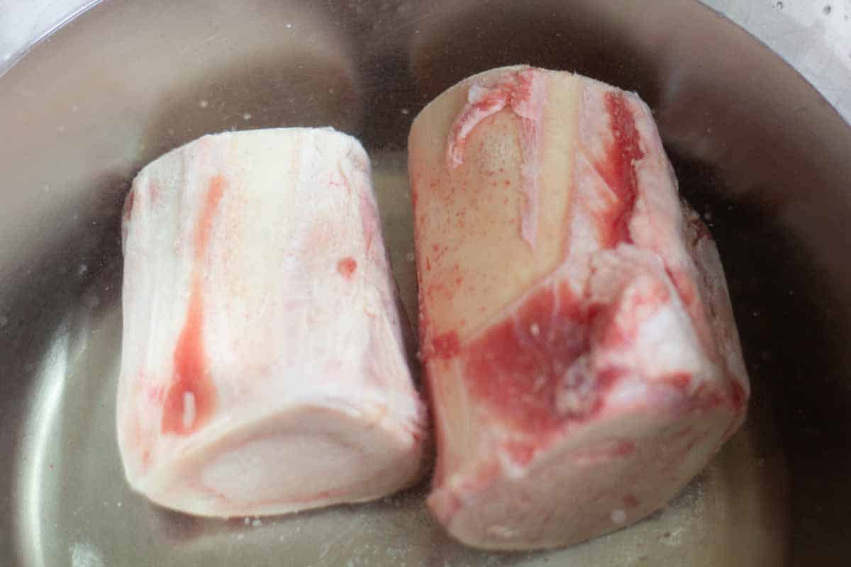 beef marrow bones soaking in a bowl of water