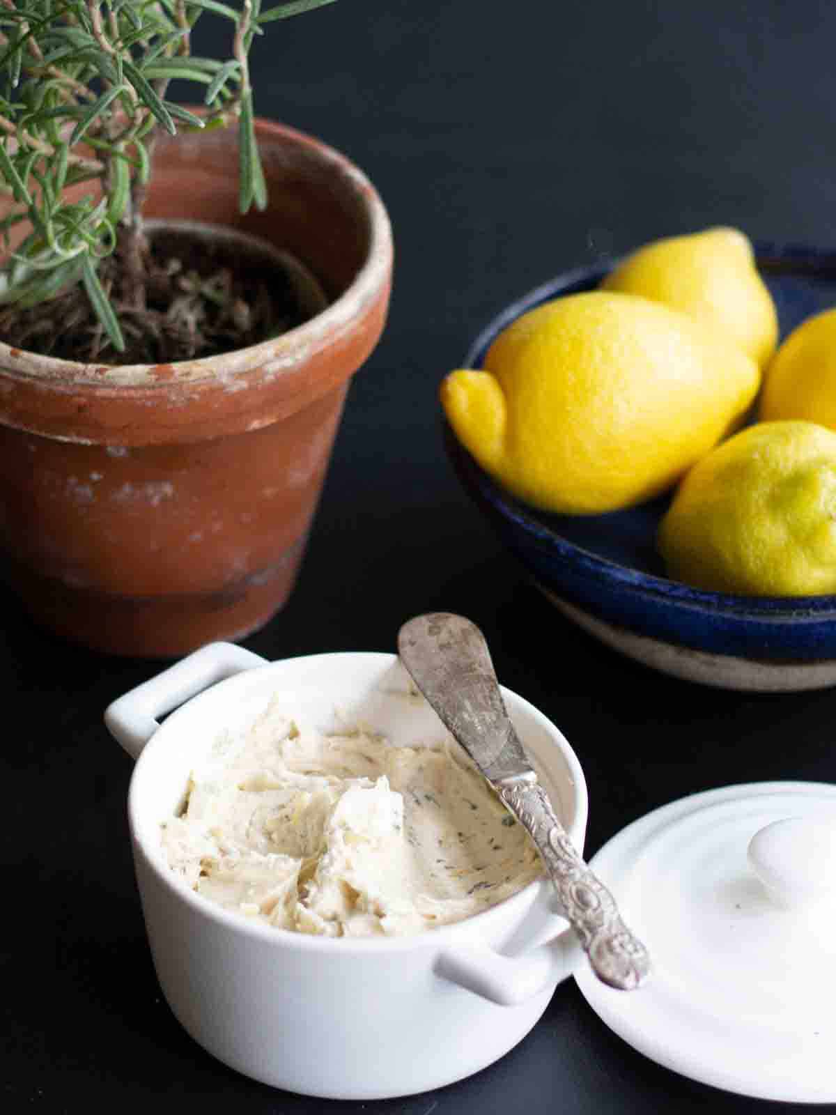 Bonemarrow butter in a white ramekin beside a bowl of lemons and fresh rosemary