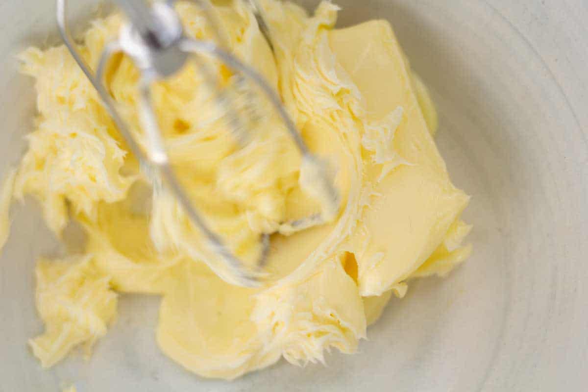 an electric mixer whipping butter in a white ceramic bowl